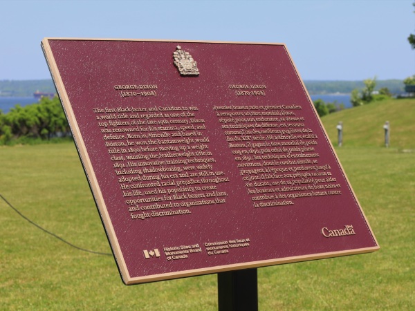 Une plaque commémorative en bronze avec des mots inscrits dessus, herbe et ciel bleu