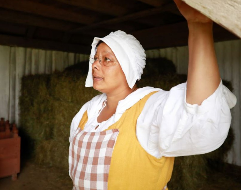 Une femme en vêtements historiques à l'intérieur d'une grange
