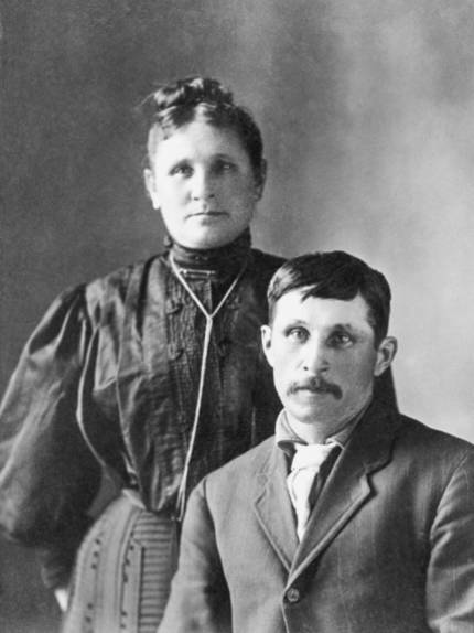 Historic black and white image of two people sitting for their portrait