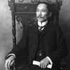 Black and white photo of a man seated on a chair