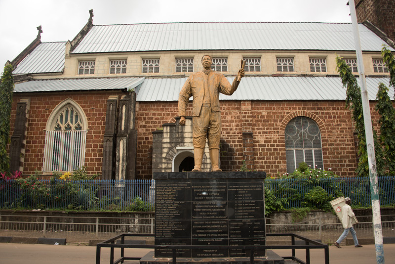 A statue of a man standing, in front of a building