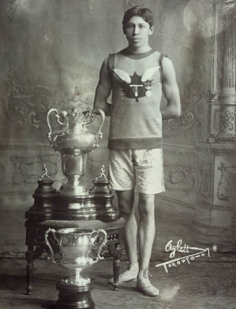 Black and white photo of a man posing next to a trophee