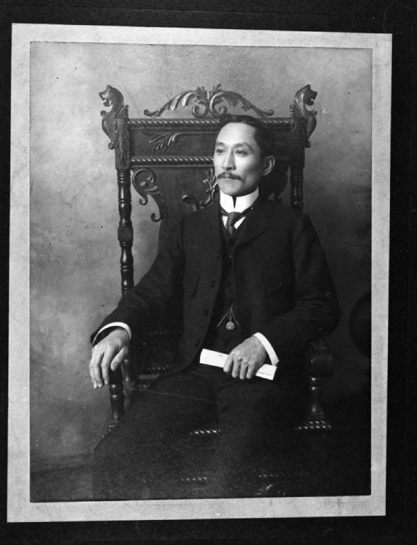 Black and white photo of a man seated on a chair