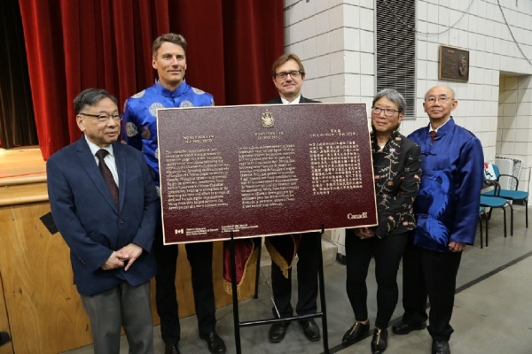 Des gens présentent une plaque commémorative