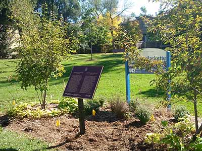 Une plaque commémorative en bronze sur son socle dans un décor verdoyant