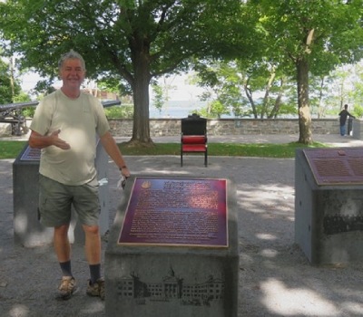 A man standing beside a bronze commemorative plaque