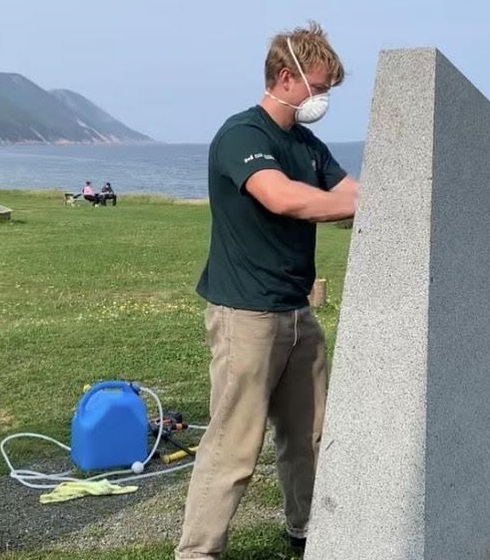 A student refurbishing a commemorative bronze plaque