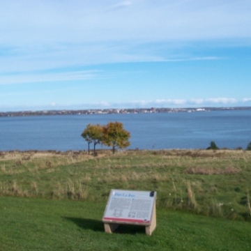 Landscape of land and water with a commemorative plaque installed on grass
