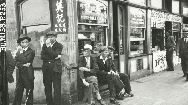 Photo en noir et blanc de quelques hommes près du coin d'un immeuble
