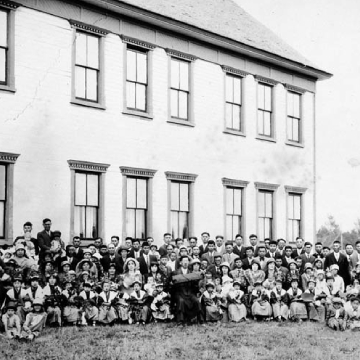 Un groupe d'immigrants japonais devant un bâtiment à Raymond, Alberta