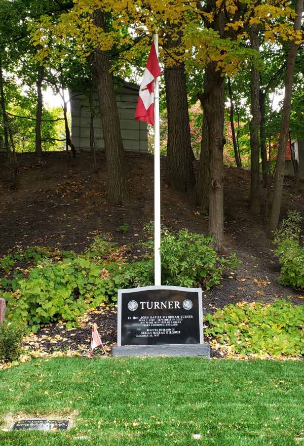 A gravesite surrounded by trees and a canadian flag