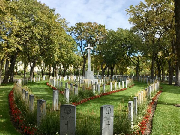 Many funerary monuments in a cemetery, surrounded by green landscape