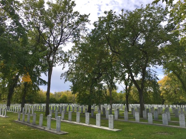 Plusieurs monuments funéraires dans un cimetière, entouré d'un paysage verdoyant