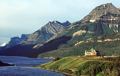 A large building siting on a cliff and surrounded by mountains and water, see from afar