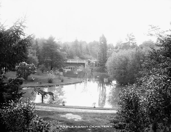 Black and white photo of a cemetery with a pond