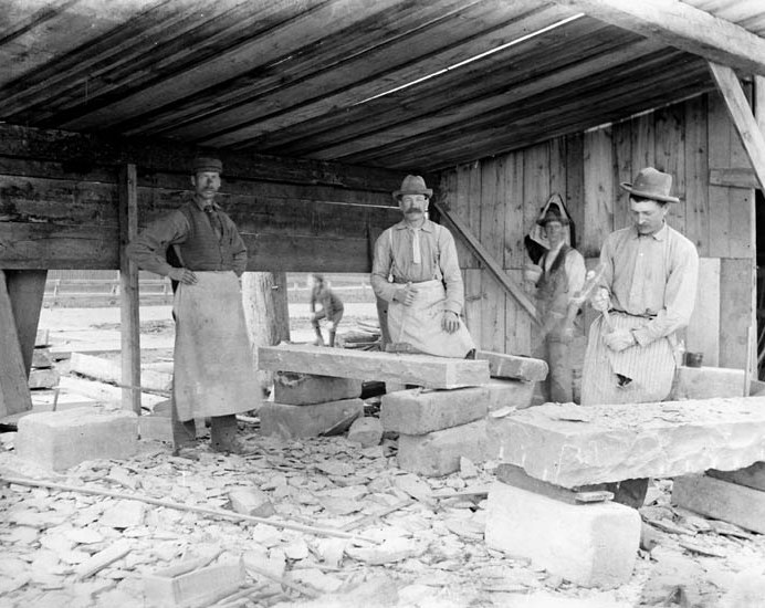 Black and white photo of four stone cutters at work during the construction of the Victoria Memorial Museum