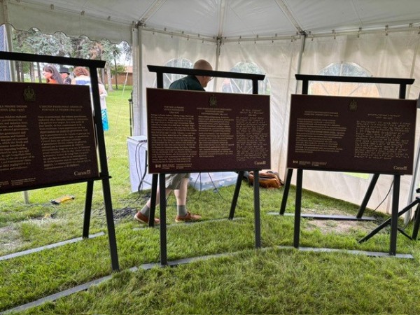 Three commemorative plaques on easel are shown under a marquee