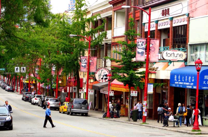 A street in a chinatown, buildings, cars and pedestrians