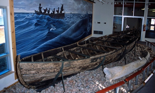 Interior view of a visitor center and a wooden boat on display