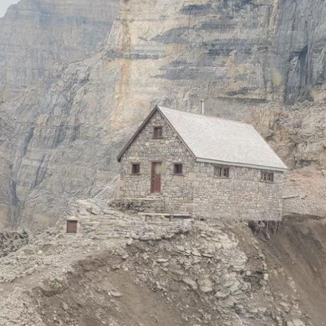 A stone refuge is located on a mountain pass at very high altitudes.