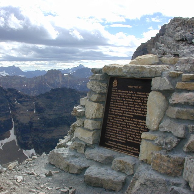 A bronze commemorative plaque is installed on a stone base, on a mountain pass.