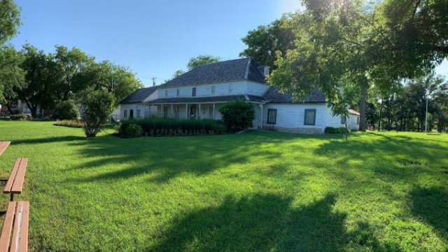 Une grande maison blanche dans un environnement d'herbe verte