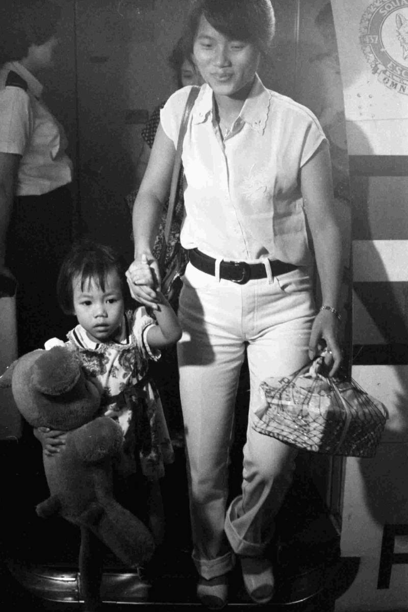 Black and white photo of an adult and a child exiting a plane