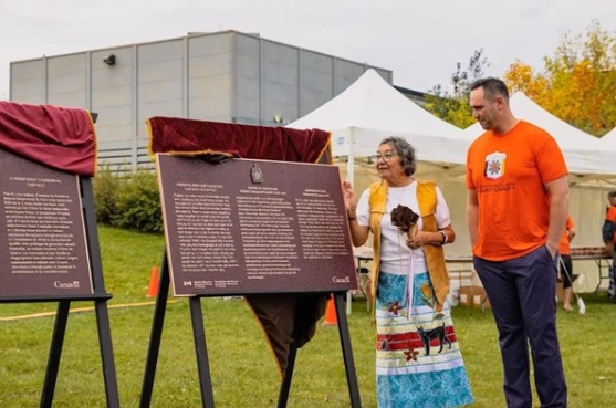 Deux personnes se tiennent à côté de plaques commémoratives lors d'un événement