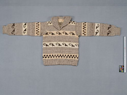 A cowichan sweater on a grey surface. The sweater shows various motifs.
