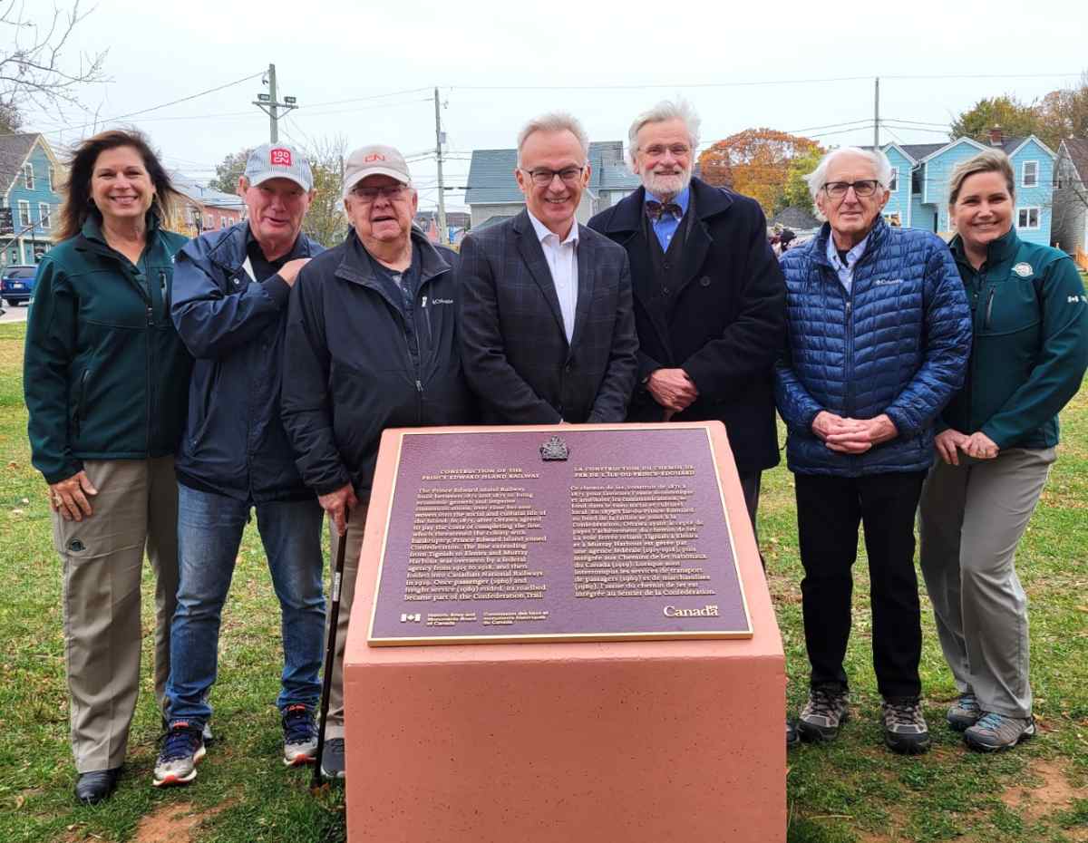 A group of people standing beside a commemorative plaque installed on a block of rock