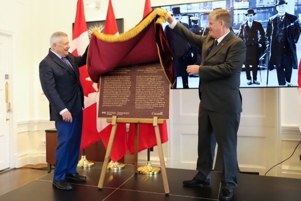 Two persons unveiling a commemorative plaque for the Establishment of the High Commission of Canada in the United Kingdom National Historic Event