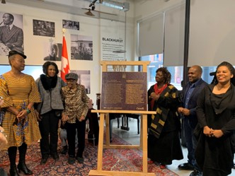 A group of people are standing near a commemorative plaque placed on an easel