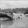 Soldiers disembark from a boat onto a beach, 1944