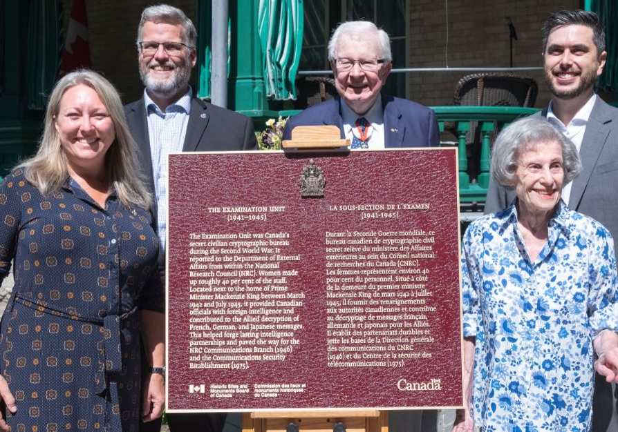 Five people beside a commemorative plaque
