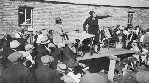 A women speaks to a crowd gathered around her, circa 1931