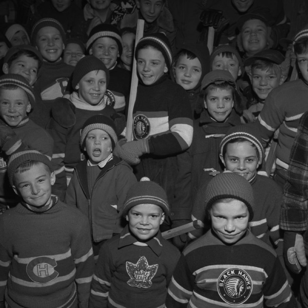 Un groupe d'enfant portant différents chandaisl de la Ligue nationale de hockey, 1956