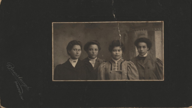 Photographie sépia de quatre personnes habillées professionnellement, vers 1908