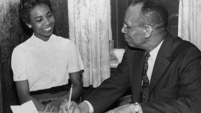 A men and a women are sitting at a desk and signing papers