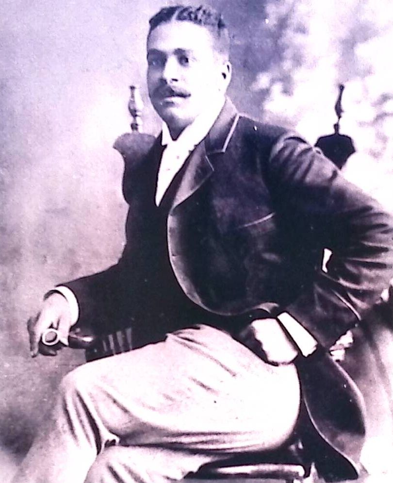 Un homme noir en habit est assis sur une chaise