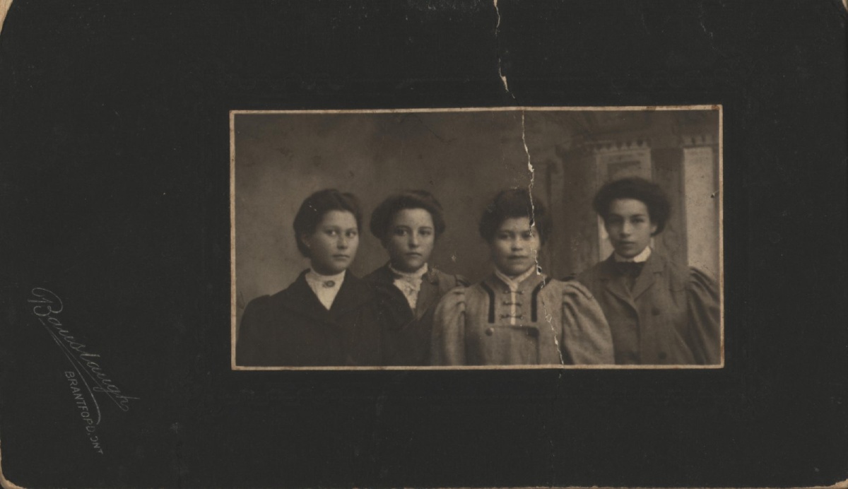 Photographie sépia de quatre personnes habillées professionnellement, vers 1908