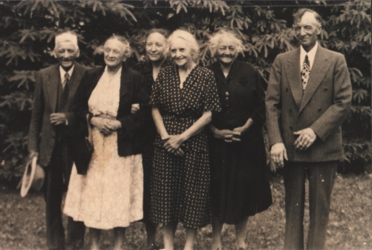 Photo sépia de six personnes d'un âge avancé se tenant debout l'un à côté de l'autre en souriant