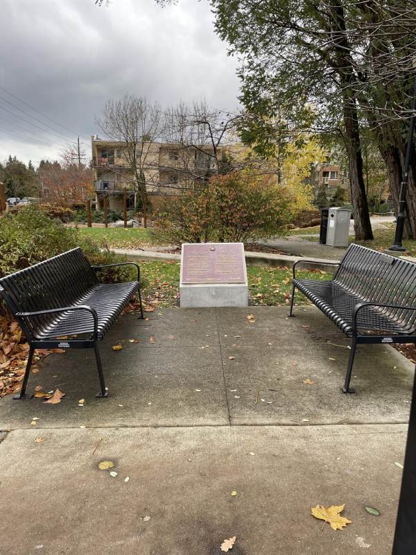 Two benches and a commemorative plaque on a stand