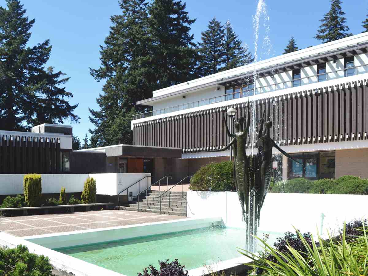 L'extérieur d'un bâtiment à l'architecture intéressante, agrémentée de verdure, d'une fontaine et d'un bassin