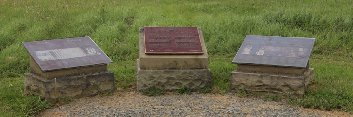 Une plaque commémorative et des panneaux d'informations historiques