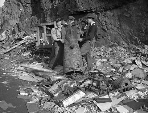 Four men hold up a large piece of a torpedo after the German U-boat attacks.