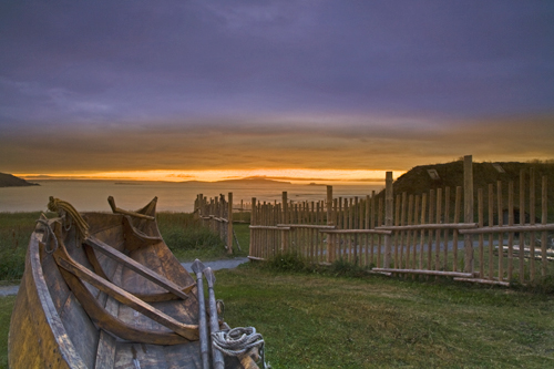 Sunset landscape near water and wooden boat and fence