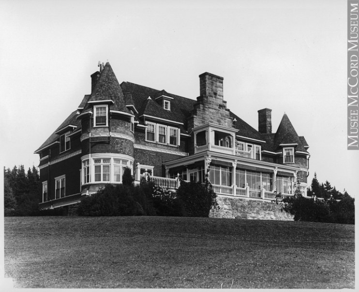 A large house built in the 1890s, with circular towers, circa 1915