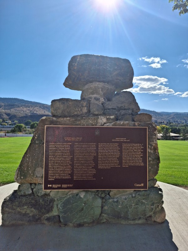 A commemorative plaque for the Former Kamloops Indian Residential School is installed on a monument made of stones