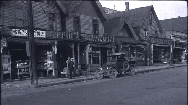 Black and white photo of a chinatown with buildings and cars