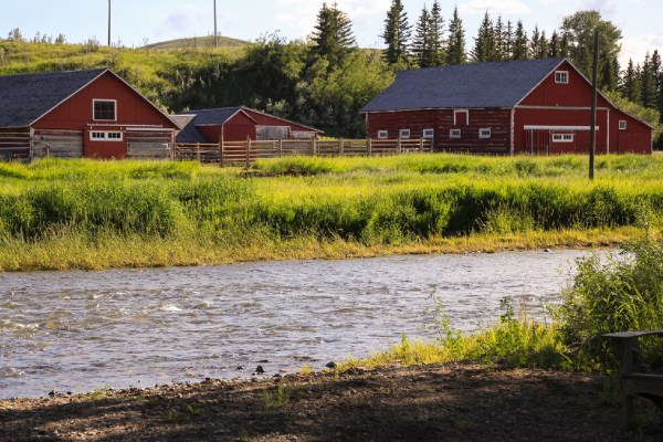 Bâtiments patrimoniaux et ferme derrière une rivière au lieu historique national du Ranch Bar U